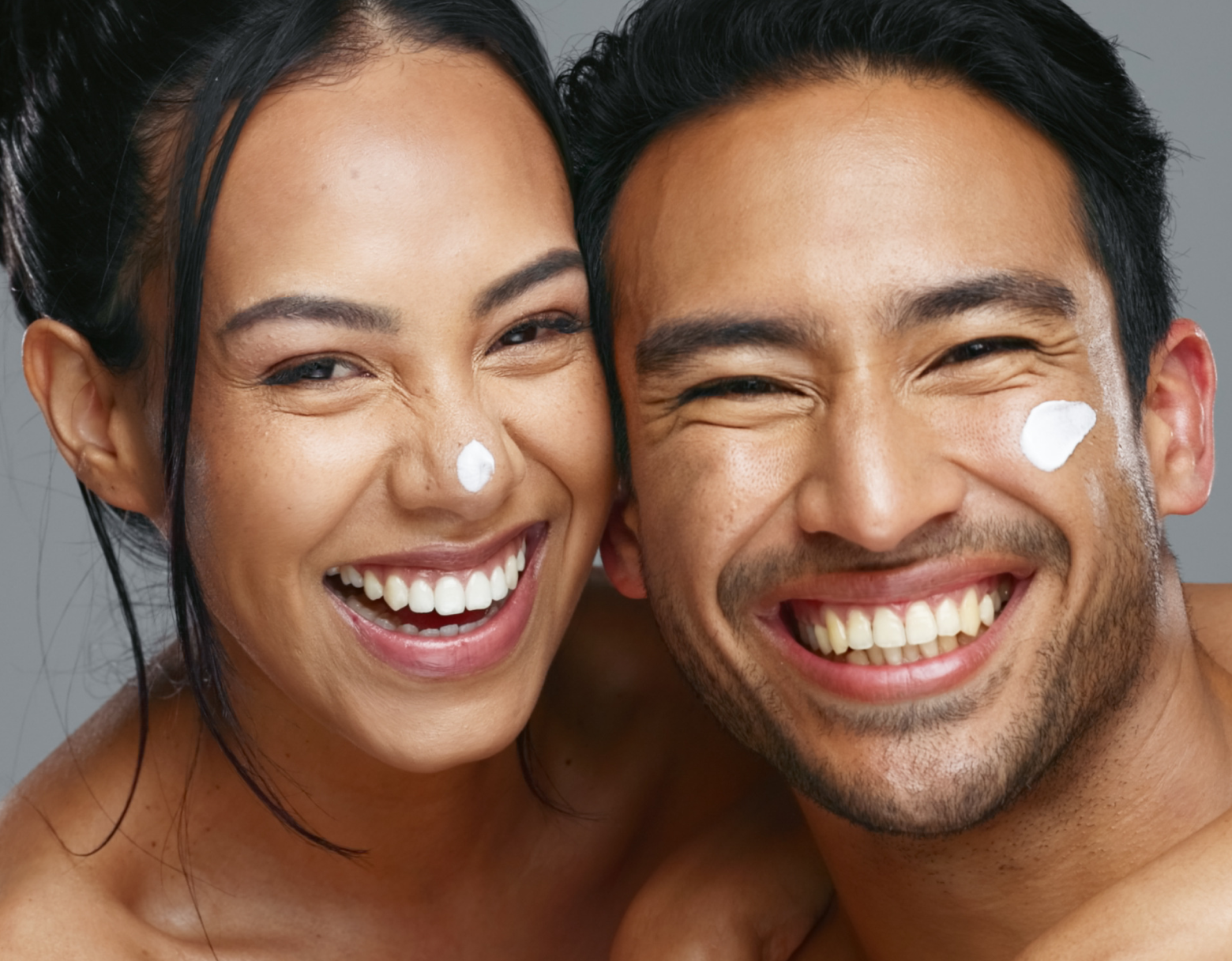 Smiling couple with glowing skin applying Pendrell skincare cream, representing hydration and radiance